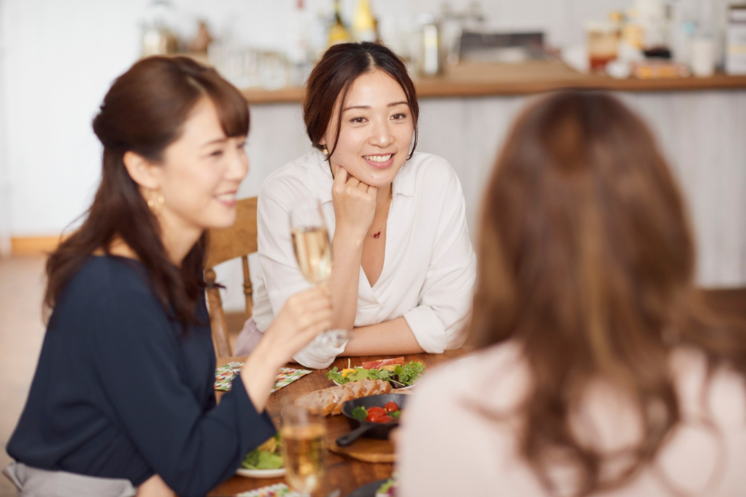 テーブルを囲んで笑顔で話す3人の女性たち