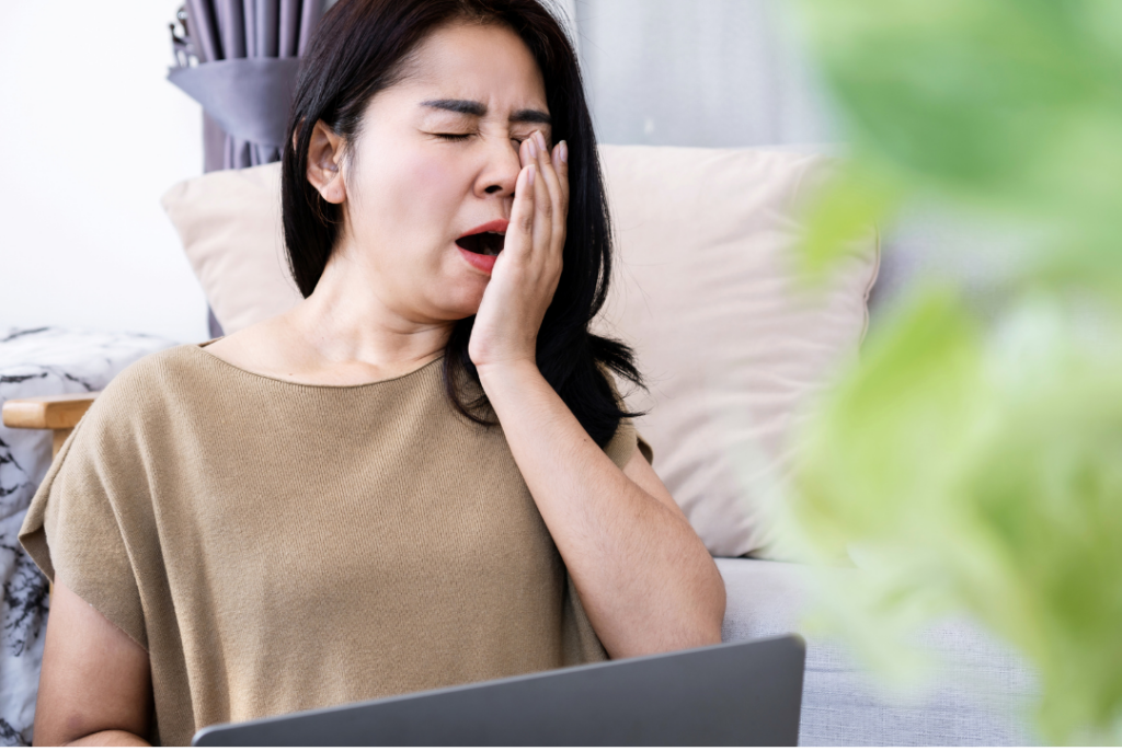 牛久エステTMR MizueがNMNで根本解決。疲れてあくびをする50代のアジア人女性。更年期による疲労感、肌のくすみ、だるさ、そして肌のハリ不足に悩み、諦めかけている様子。細胞の居眠り、アンチエイジング。
