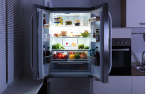 夜、暗いキッチンで開いた冷蔵庫の光に照らされる食べ物のイメージ